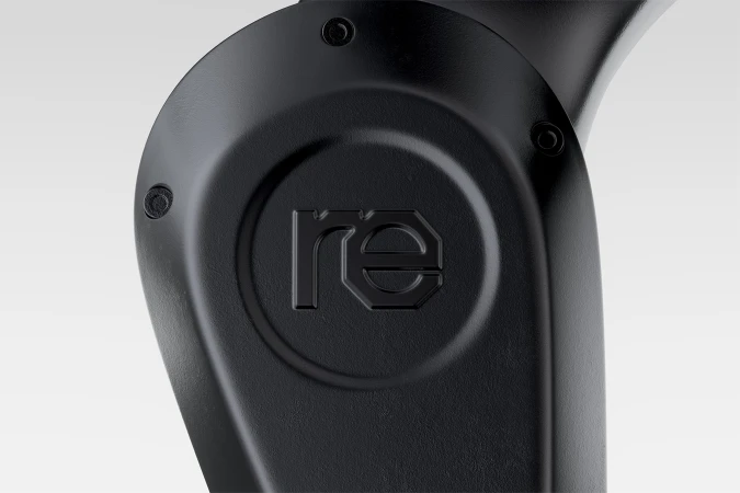 Close-up of a matte black curved hardware component featuring an embossed lowercase re logo and industrial screws.