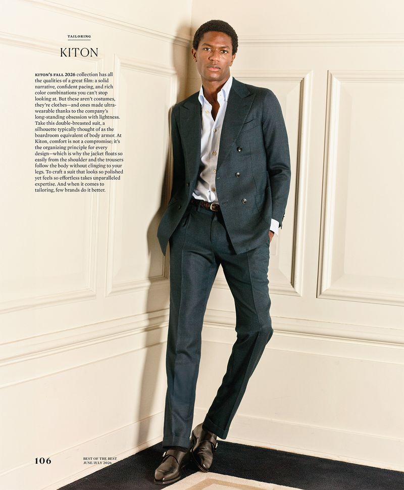 Model Hamid Onifadé wearing a tailored Kiton double-breasted suit while leaning against a cream paneled wall.
