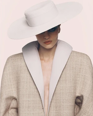 Model wearing a wide-brim white hat and textured beige coat against a light studio background for Harper's Bazaar Germany.