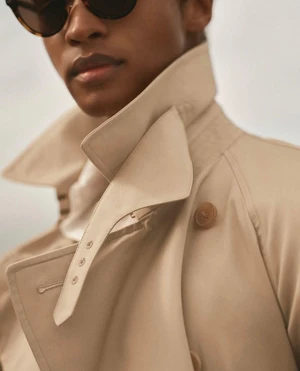 Stan Taylor wearing a beige Ralph Lauren Purple Label trench coat with an upturned collar and sunglasses.