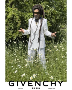 Don Letts standing in a meadow of white daisies wearing a white double-breasted suit and sunglasses for Givenchy.