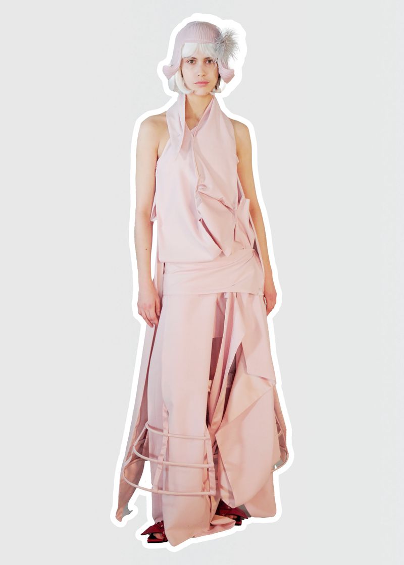 Model wearing a pale blush layered deconstructed dress with a wire frame skirt detail and matching knit cloche hat.