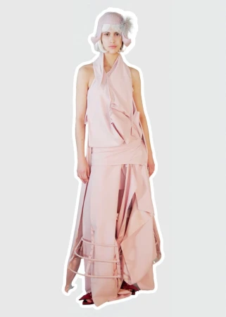 Model wearing a pale blush layered deconstructed dress with a wire frame skirt detail and matching knit cloche hat.