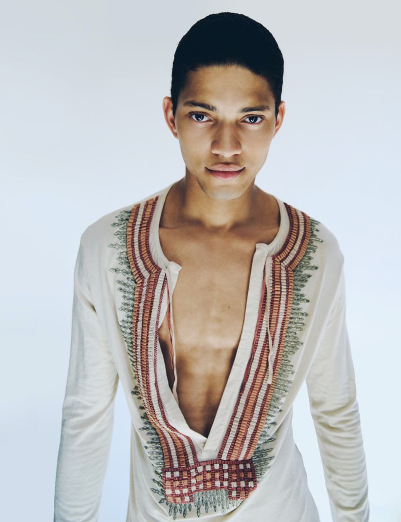 Model Jeranimo van Russel wearing an embroidered deep v-neck tunic against a bright white seamless background.