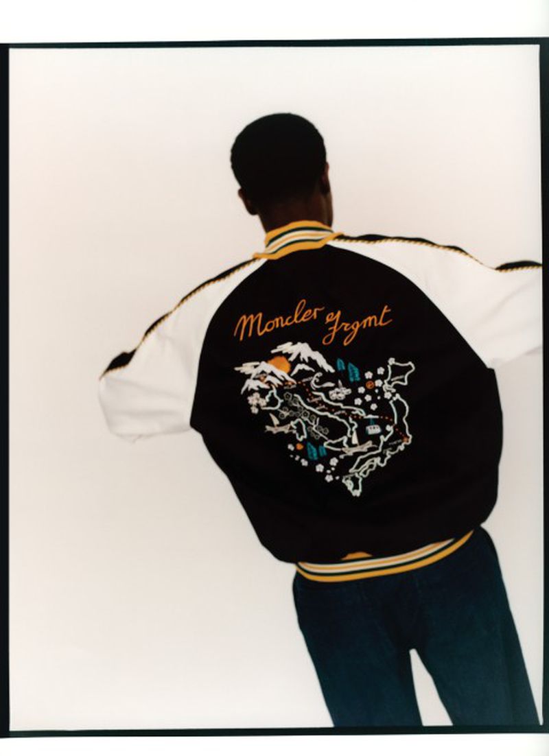 Model Momo Ciss seen from behind in an embroidered black and white Moncler jacket against a white studio background.