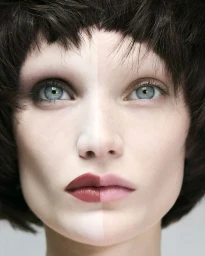 Close-up portrait of a woman with contrasting split makeup and dark layered hair for Twin Magazine
