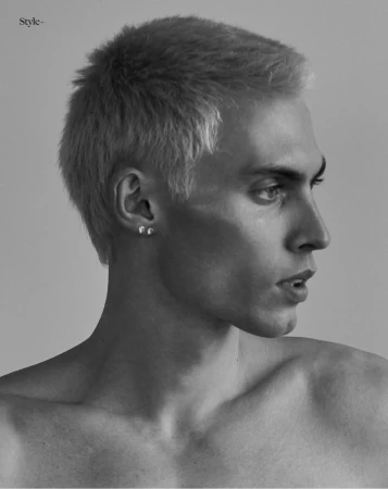 Black and white profile portrait of model Arnau Sarda with short bleached hair against a seamless grey backdrop.