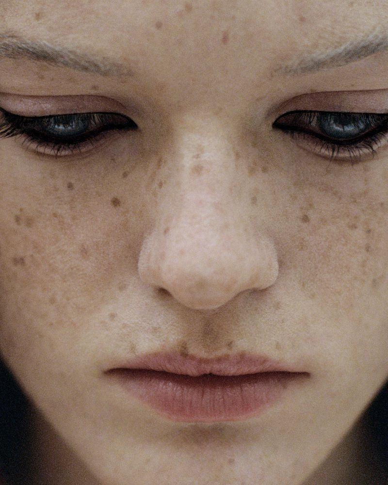 Close-up portrait of a woman's face with heavy freckles and dark winged eyeliner for Vogue Australia