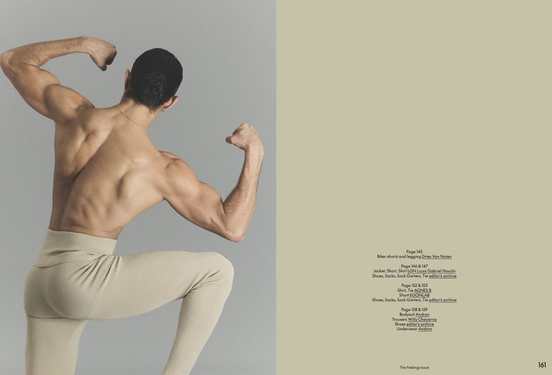 A shirtless muscular man seen from behind flexing his arms in beige ribbed leggings across an editorial magazine spread.
