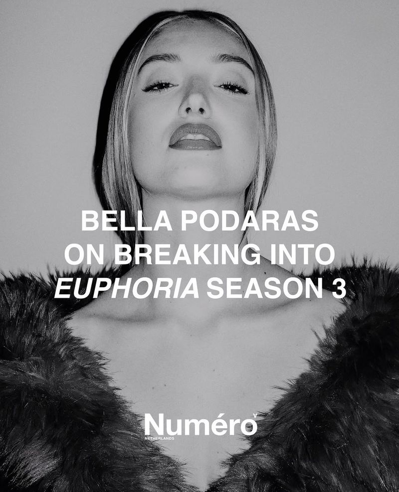 Portrait of Bella Podaras wearing a dark fuzzy top against a plain light background for Numero Netherlands.