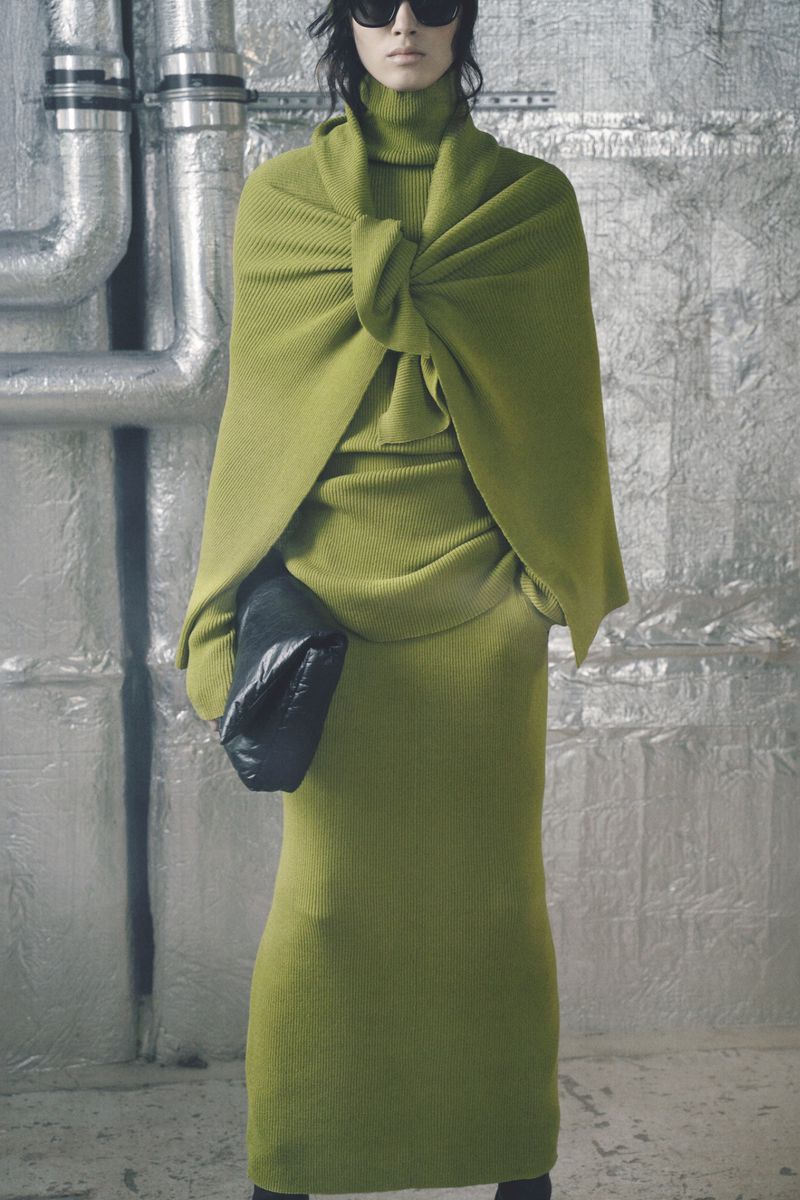 Model Svetlana Lethelier wearing a green knit ensemble and sunglasses with a black clutch against an industrial silver foil backdrop.