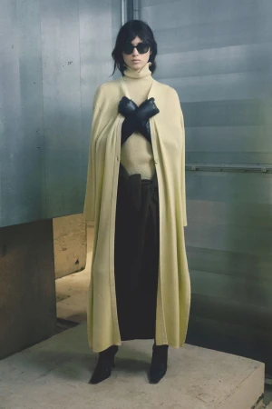 Model Svetlana Lethelier wearing a butter-yellow knit coat, turtleneck, black gloves, and sunglasses for Christian Wijnants.