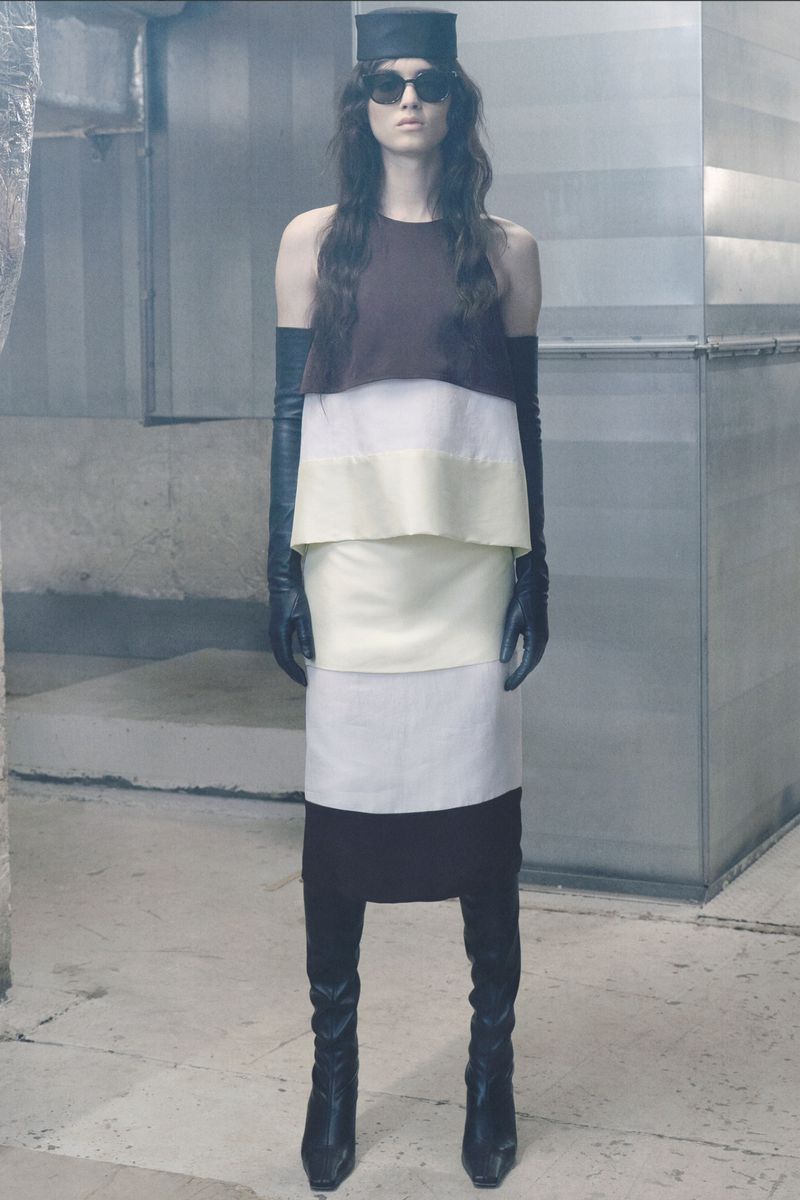 Model Svetlana Lethelier in a color-blocked layered dress with black leather opera gloves, boots, and hat for Christian Wijnants.