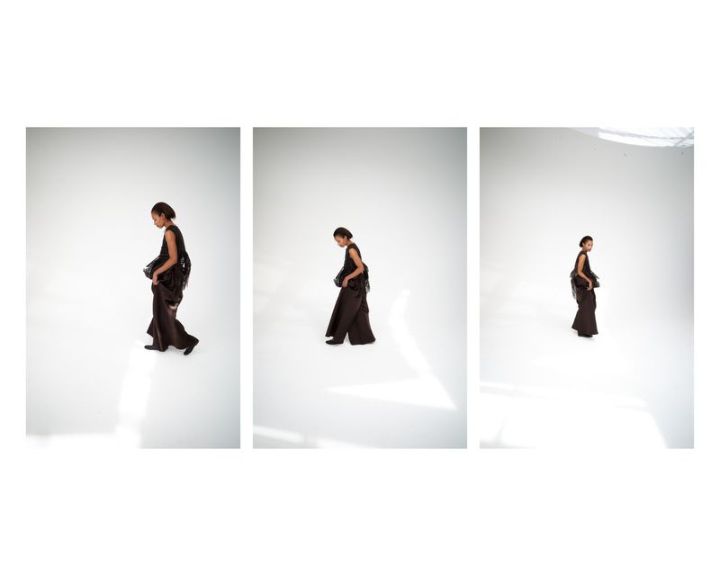 Triptych of model Romae Gordon in a sleeveless dark ensemble walking across a bright white studio floor.
