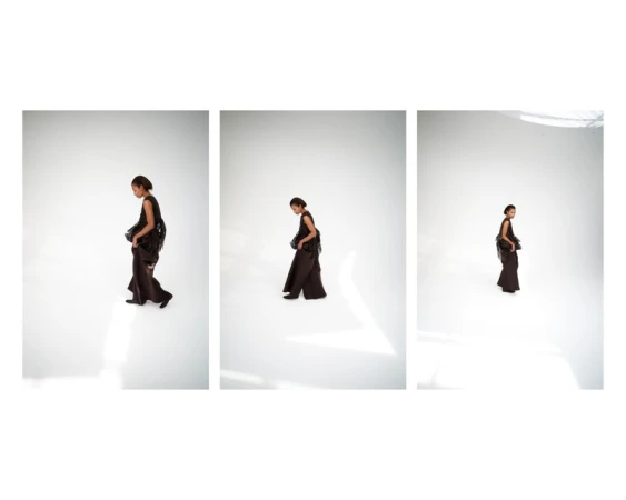 Triptych of model Romae Gordon in a sleeveless dark ensemble walking across a bright white studio floor.
