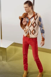 Model Pavlo Stinyk in red trousers, patterned argyle cardigan, and tan boots for Acne Studios lookbook.