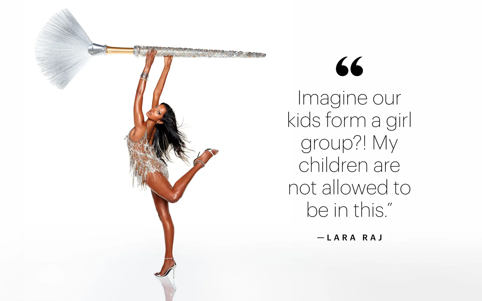 Lara Raj balancing on one leg holding an oversized glittering fan makeup brush above her head against a white background.
