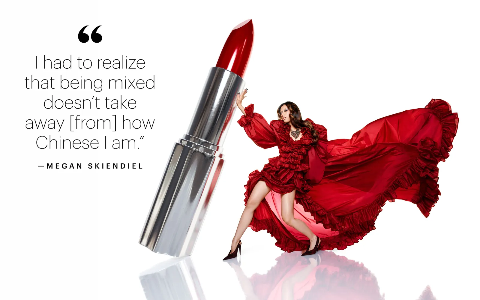 Megan Skiendiel in a flowing red ruffled gown posing beside a giant silver lipstick tube against a white seamless background.