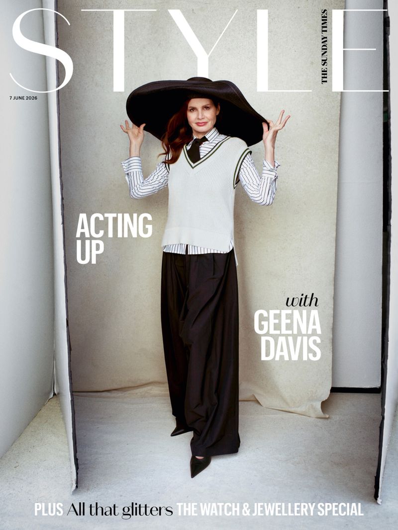 Geena Davis poses in an oversized black hat, white sweater vest, and wide-leg black trousers for The Sunday Times Style cover.
