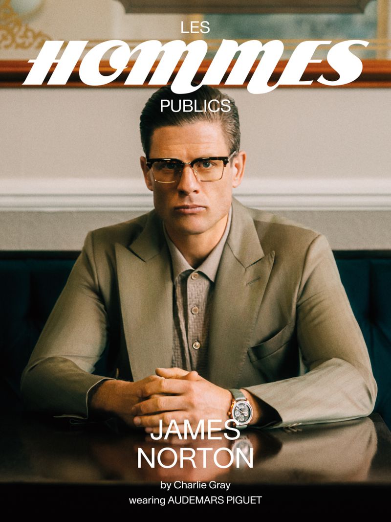 Portrait of actor James Norton wearing a suit jacket and glasses, seated at a dark table for Les Hommes Publics #16 2026 Covers.