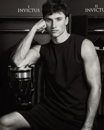 Monochrome portrait of a man in a black tank top resting by an Invictus trophy fragrance bottle in a locker room.