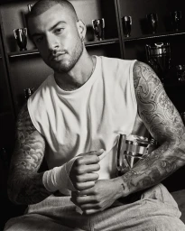 Black and white portrait of a tattooed man in a white sleeveless shirt with wrapped wrists holding a trophy.