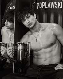 Monochrome portrait of model Giuliano Poplawski holding a trophy-shaped Rabanne Invictus Elixir bottle in a locker room setting.