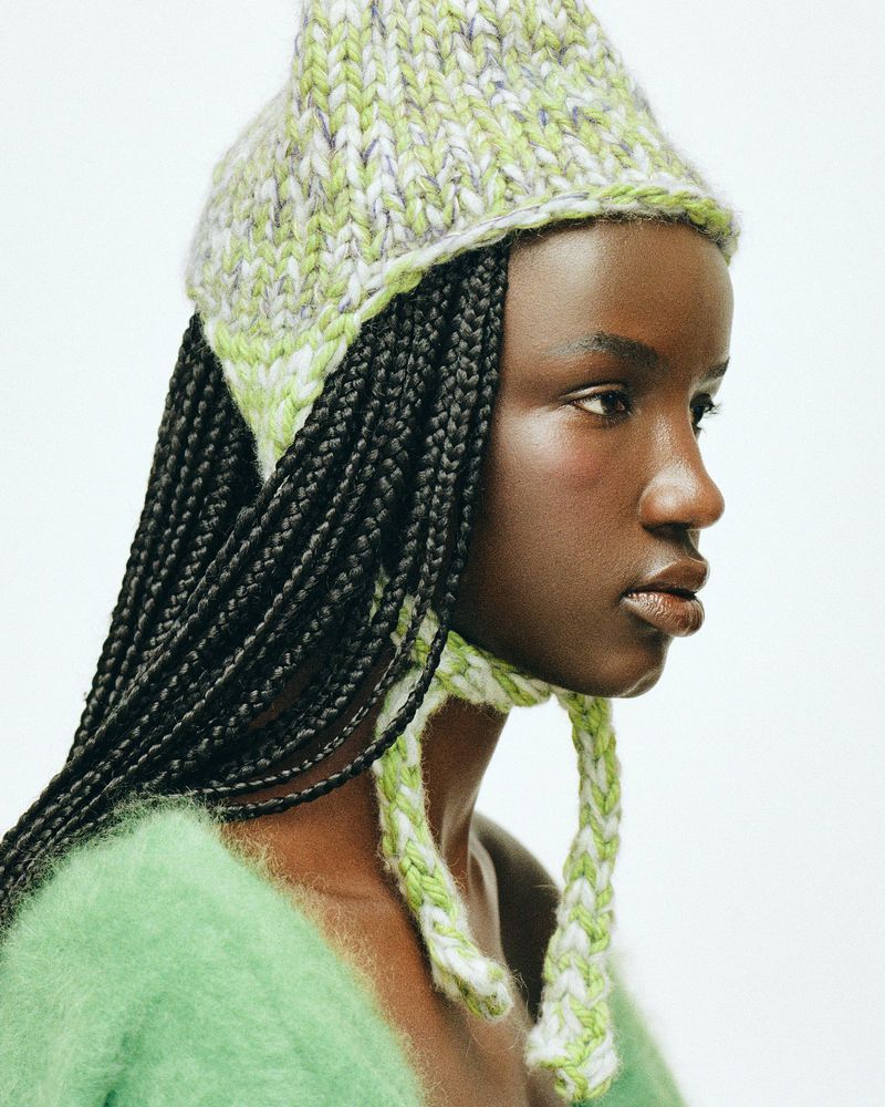 Close-up portrait of an African American woman wearing a knitted hat, showcasing fashion and beauty against a white background.