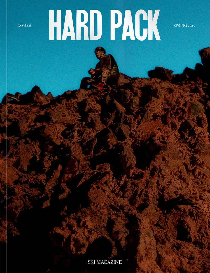 Magazine cover depicting a person seated atop a rocky mountain, set against a clear blue sky with 'HARD PACK' title text.