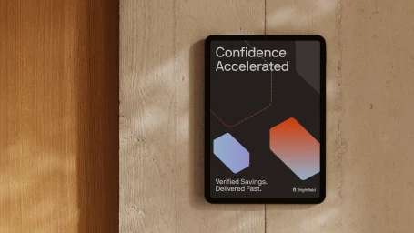 Digital tablet displaying Brightfield brand identity graphics mounted against a concrete wall and warm wood paneling.
