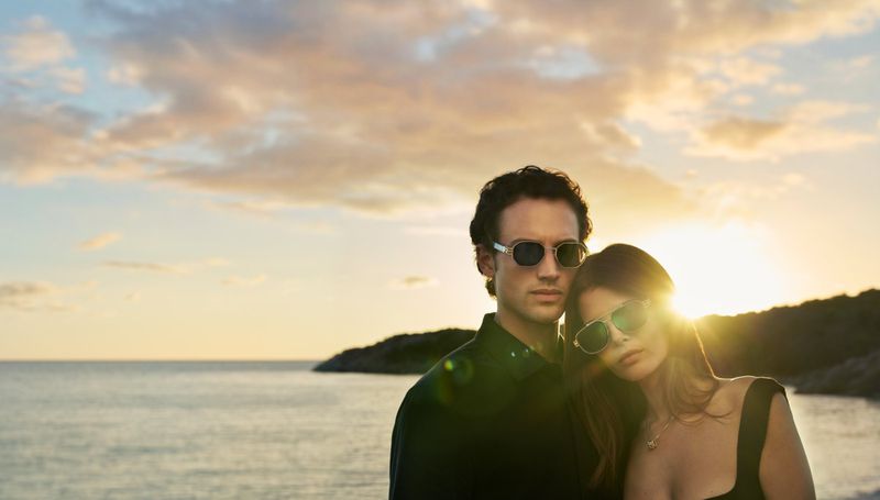 Federico Novello and Monica Cima wearing luxury sunglasses during sunset at a coastal beach for Fred.