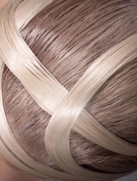 Close-up of sculpted blonde hair styled in overlapping crisscross strands over a sleek base.