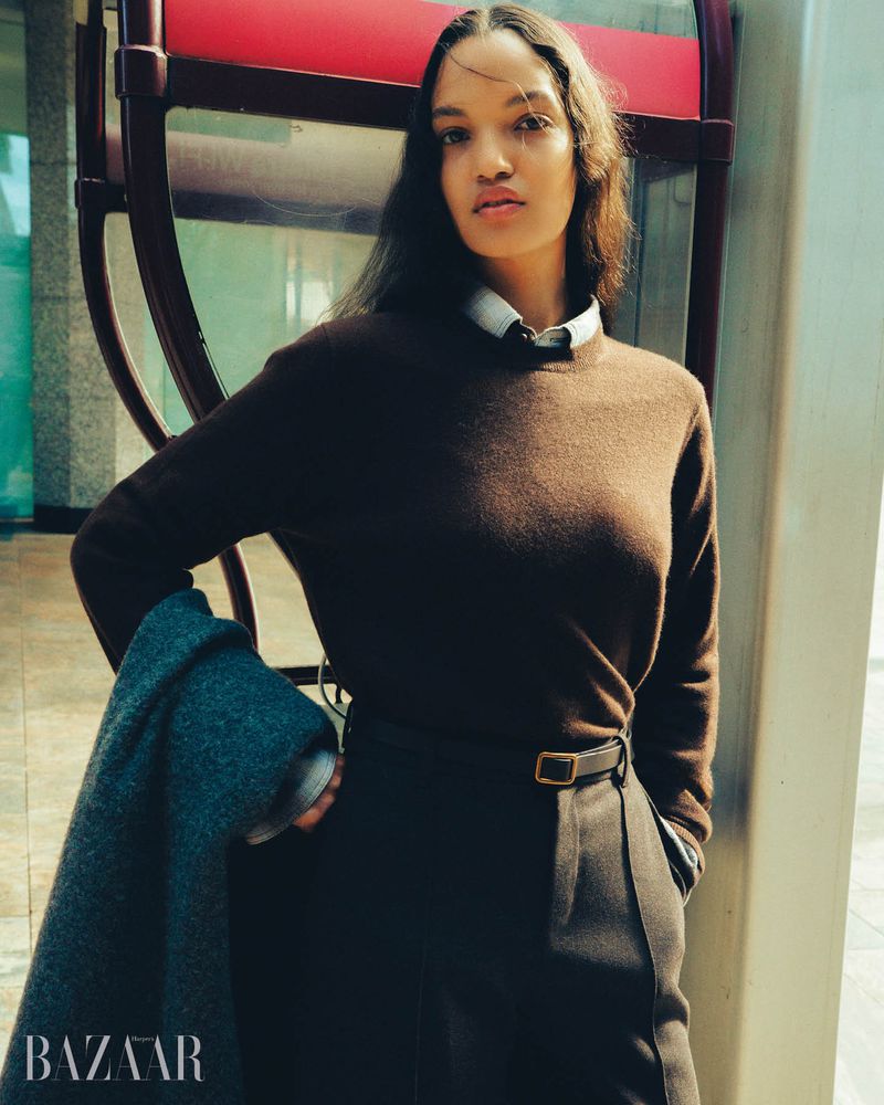 Model wearing a brown cashmere sweater, collared shirt, and dark tailored trousers posing outdoors for Harper's Bazaar Australia.