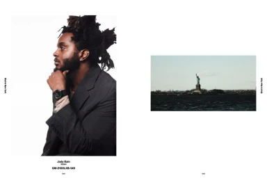 Magazine spread featuring a side profile portrait of a Black man wearing a black watch beside a distant view of the Statue of Liberty.