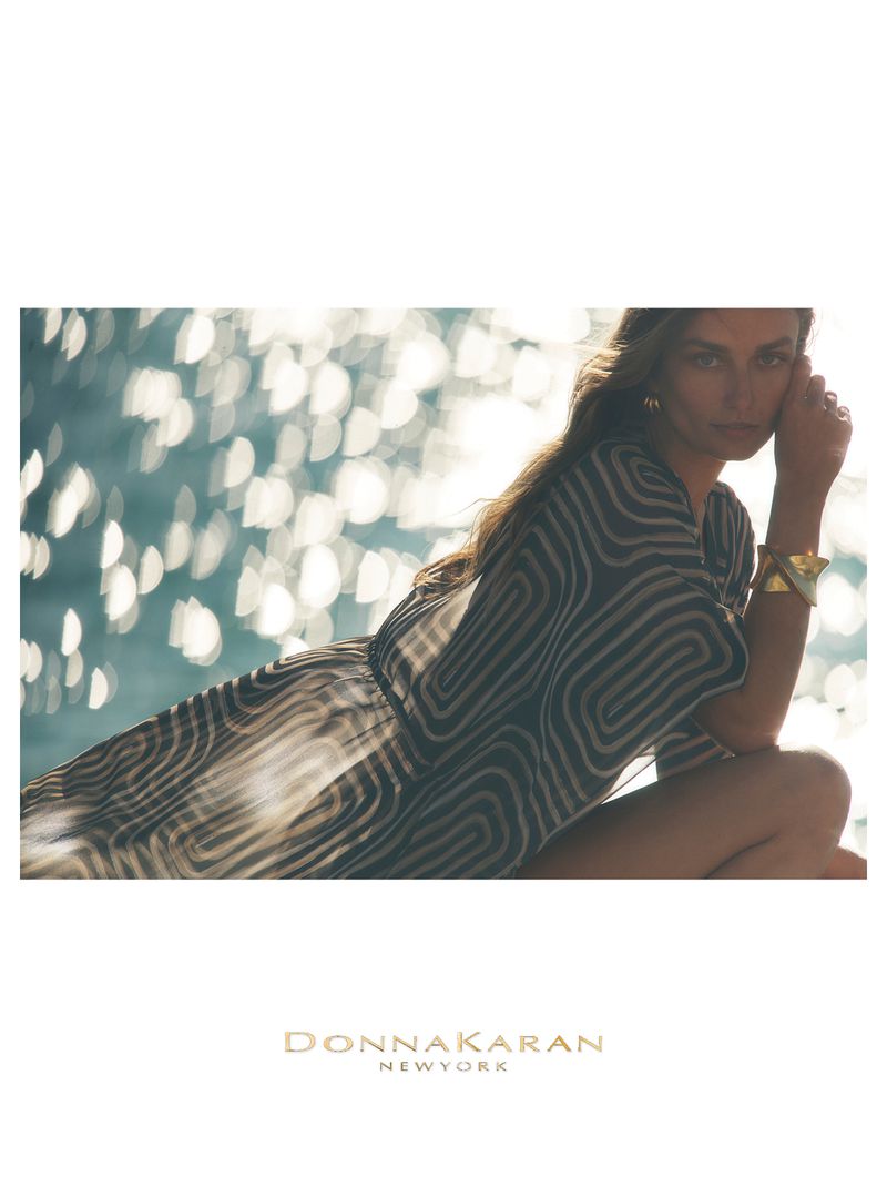 Model Andreea Diaconu in a geometric patterned tunic dress and gold cuff bracelet by sparkling water for Donna Karan.