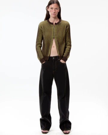 Model Elle Dawson standing in a yellow-green ribbed zip cardigan and wide-leg dark denim jeans against a white background.