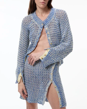 Model wearing an open blue and white knit cardigan and matching slit mini skirt against a white studio background.