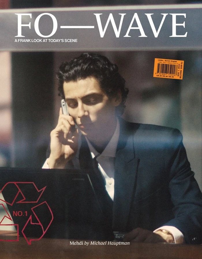 Magazine cover of Mehdi Abouzaid talking on a silver cell phone behind a laptop in a dark tailored suit by Michael Hauptman.