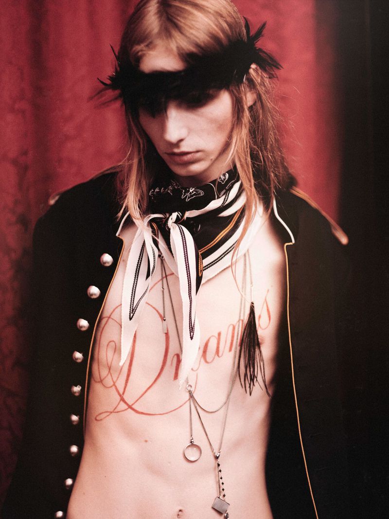 Model with feather headband wearing dark jacket and neck scarf in Ann Demeulemeester SS26 backstage