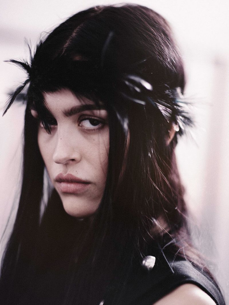 Amelia Gray wearing a black feather headpiece and black sleeveless top at the Ann Demeulemeester SS26 backstage.