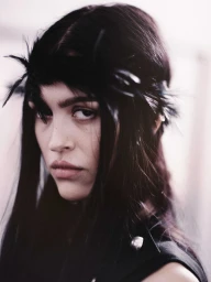 Amelia Gray wearing a black feather headpiece and black sleeveless top at the Ann Demeulemeester SS26 backstage.