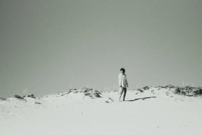 Model Maja Zimnoch stands atop a pale sandy dune against a vast sky in an outdoor fashion shoot by Dorota Szulc.