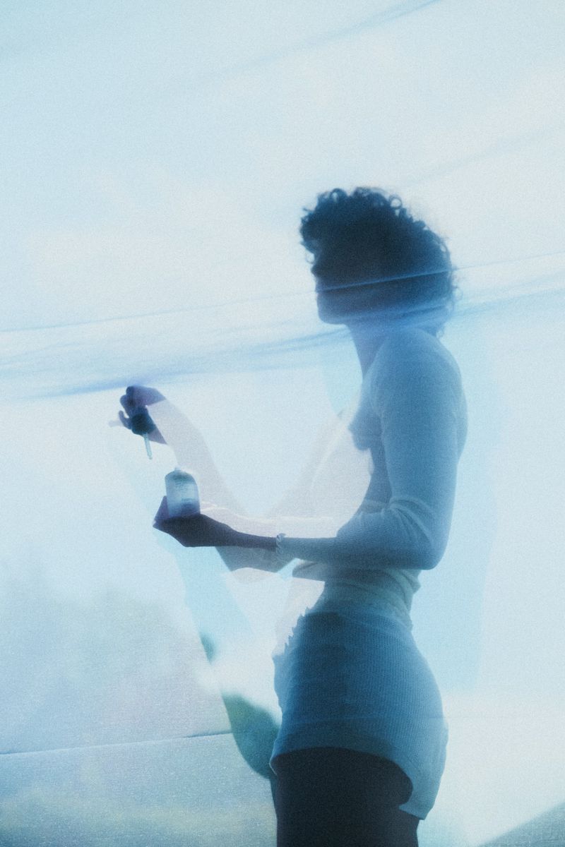 Silhouette of model Maja Zimnoch viewed through sheer pale blue fabric wearing shorts and a long-sleeve top.