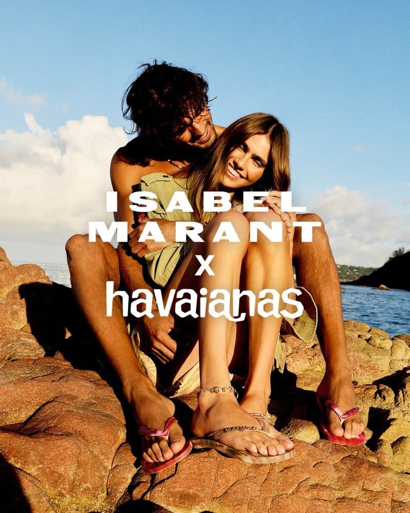 Marlon Teixeira and Mia Armstrong seated on coastal rocks wearing flip-flops for the Isabel Marant x Havaianas campaign.