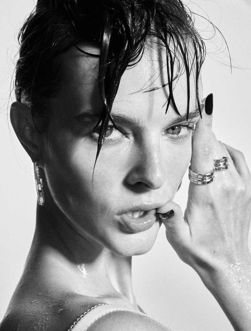 Black and white close-up portrait of a woman with wet hair strands across her forehead wearing silver rings.