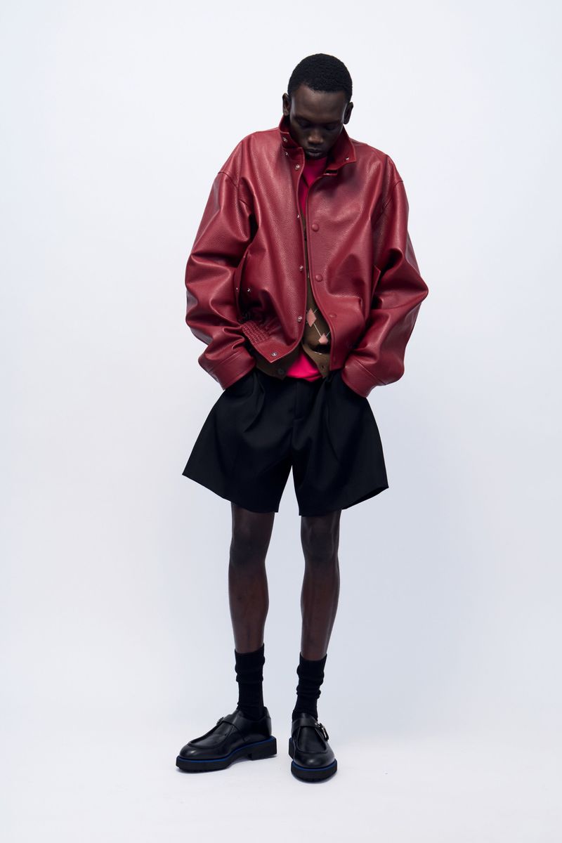 Model Bukwop Kir wearing an oversized burgundy leather jacket and black tailored shorts against a white backdrop for Lanvin.