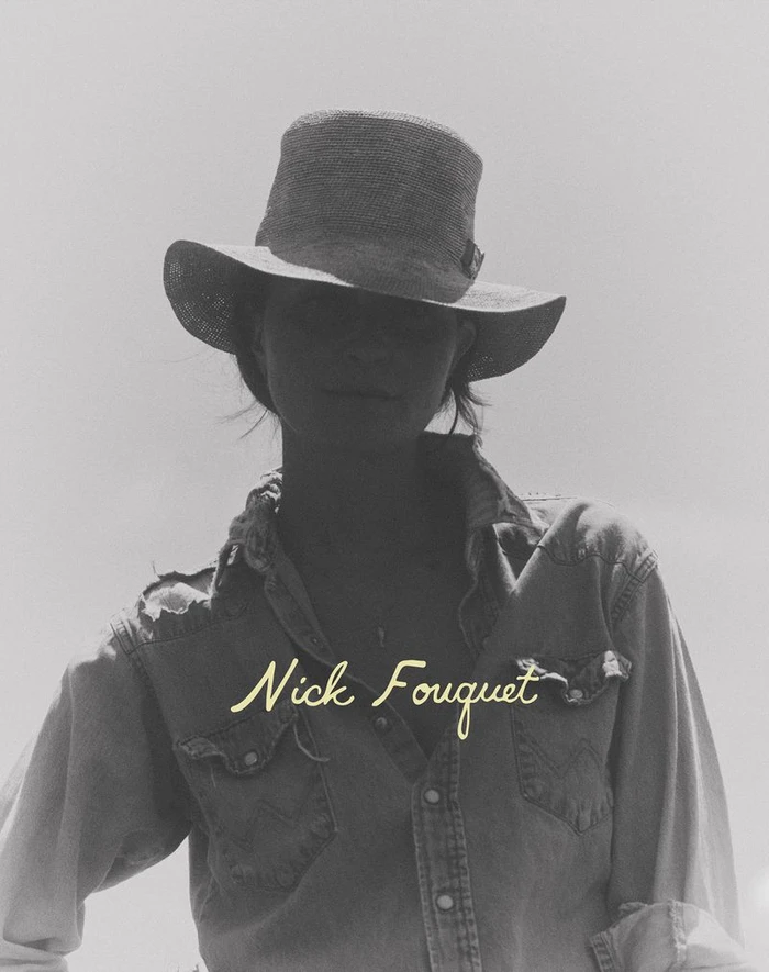 Monochrome portrait of a model wearing a wide-brim hat and distressed denim western shirt with Nick Fouquet text.