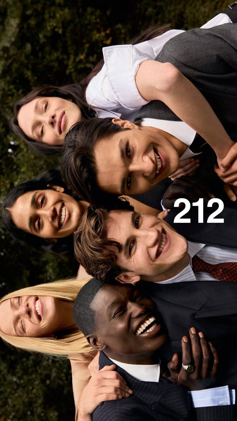 Group of smiling diverse models huddled together outdoors wearing formalwear for Carolina Herrera 212 Men Parfum