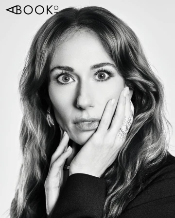 Black and white portrait of Jessica Blair Herman looking forward with hands on her cheek against a studio backdrop.