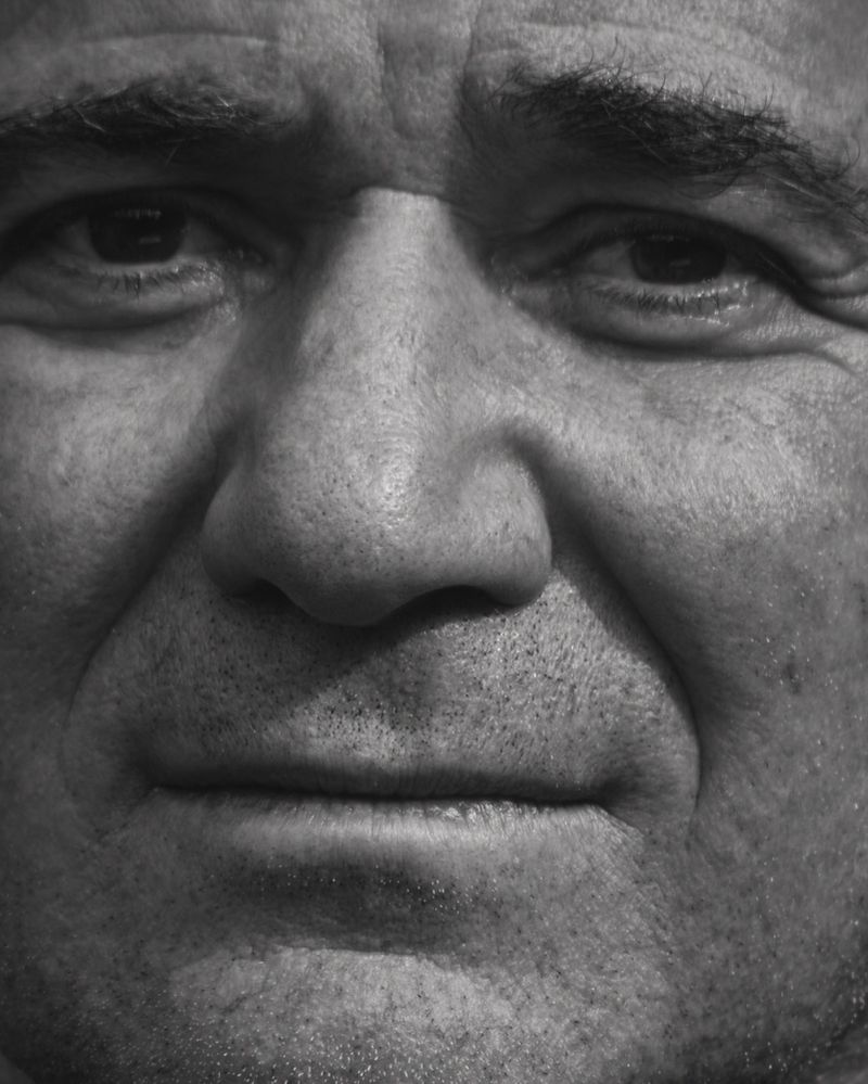 Monochrome extreme close-up portrait of a mature man's face showing detailed facial features and skin texture.